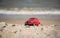 Red model of a retro car on a background of a sandy beach in Los Angeles