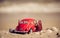 Red model of a retro car on a background of a sandy beach in Los Angeles