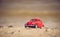 Red model of a retro car on a background of a sandy beach in Los Angeles, California, USA