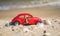 Red model of a retro Volkswagen Beetle on a background of a sandy beach in Los Angeles, California