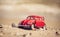 Red model of a vintage Volkswagen Beetle on a background of a sandy beach in Los Angeles