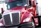 Red modern big rig semi truck with shiny grille and painted surf