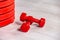 Red modern dumbbells and pancakes for dumbbells in the foreground on a wooden floor