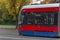 Red modern public electronic railway tram on street with forest