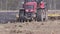 Red modern tractor with reverse plow plows the field. Farmer on a red tractor plowing the dusty arid soil. Agribusiness in the spr