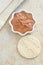 Red moroccan bentonite clay in a small white bowl and loofah sponge. Diy facial or hair mask, body wrap recipe. Natural beauty