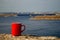A red mug with black coffee stands on a stone on a blurred background of the Volga River and Zhigulevskaya hydroelectric station.