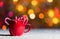 Red mug with candy canes in snow with defocussed fairy lights, bokeh in the background, Festive Christmas background