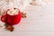 Red mug with cocoa and marshmallows, on a background of a scarf and dry leaves. Autumn mood, a warming drink