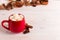 Red mug with cocoa and marshmallows, on a background of a scarf and dry leaves. Autumn mood, a warming drink