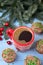 Red mug with coffee and Christmas cupcakes with chocolate cream, vertical