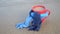 Red mug with coffee tied with blue knitted scarf stands on sandy beach