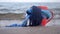 Red mug with coffee tied with blue knitted scarf stands on sandy beach