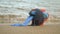 Red mug with coffee tied with blue knitted scarf stands on sandy beach