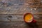 Red mug with freshly brewed coffee with appetizing crema on aged wood kitchen table. Cozy winter fall holiday atmosphere