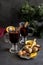Red mulled wine in glasses at black background. Fir wreath, orange, cinnamon, nuts, cone and spices