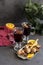 Red mulled wine in glasses at black background. Fir wreath, tray with orange, cinnamon, nuts, cone