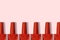 Red nail polish bottles in row on pastel pink background top view
