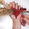 Red nails with a burgundy gradient on the background of a yellow twig with a red bow.