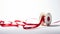 a red narrow festive ribbon elegantly arranged on a reel against a white plain paper background, for