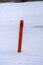 Red navigational spar buoy on a frozen lake