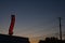 A red neon liquors store sign glowing during a sunset