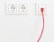 Red network cable in wall outlet for office or private home lan ethernet connection with power outlets flat view on white plaster