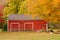 Red New England barn in autumn with colorful leaves