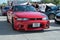 red ninth-generation Nissan Skyline GT-R33 at a Japanese sports car meet.