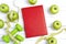 Red notepad with green dumbbells and apples with measuring tape