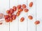 Red oblong cherry tomatoes scattered on a white background of boards. Top view