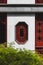 Red octagonal window on white wall of traditional house