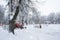 A red old tractor clears the street of snow in a snow storm. Street cleaning in winter