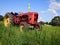 Red old tractor standing in a green field