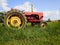 Red old tractor standing in a green field