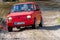 Red oldtimer car Fiat 126 overcomes water obstacle