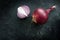 Red onion whole and halved, healthy and spicy vegetable on a dark slate background with copy space