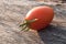 Red-orange, small tomato on a wooden background; arranged diagonally