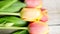 Red and orange tulip flowers in a row on wooden background in 4K VIDEO. Spring flowers.