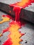 Red, orange and yellow paint dripping on a concrete slab.