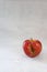 Red organic ugly apple on grey cement background with copy space. Fruit with unusual shape. Buying imperfect product to