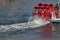 Red paddle wheel on a boat churning the water