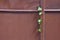 Red painted iron gate with a cross and a door handle.