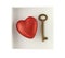 Red painted polyfoam heart and bronze key in paper box isolated on white background. View from above