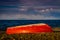 Red Painted Reverse Rowboat On Shoreline