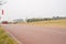 Red-painted road on withered lawn in light winter mist