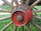Red painted wooden wheel axle with bolt + nut of an old car