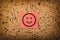 red paper with smiling face on corkboard. bulletin board