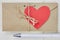 Red paper valentine in a shape of heart on vintage cardboard envelope, pen and notebook