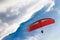 Red Paragliding Against Blue Sky with White Clouds